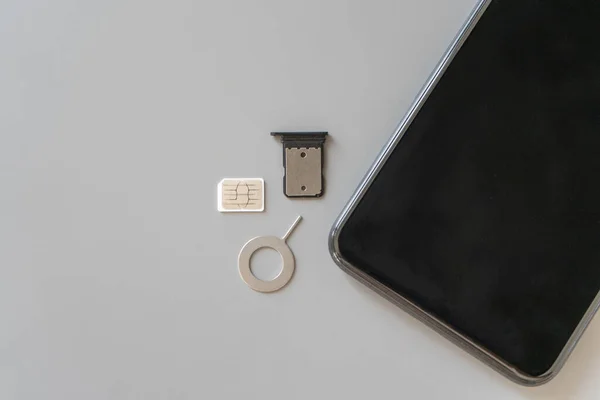 使用されるNano Sim 4Ff スロットから削除されたトレイ およびSimカードとスマートフォンを抽出するための抽出器がテーブルにあります — ストック写真