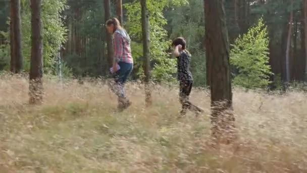 Egy nő és egy fiú sétálnak az erdőben a fák között. — Stock videók