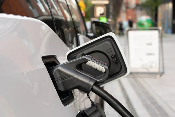 Kabloyla elektrik tedarik ünitesine bağlı modern bir elektrikli araba şehrin şarj istasyonunda pilleri şarj eder.