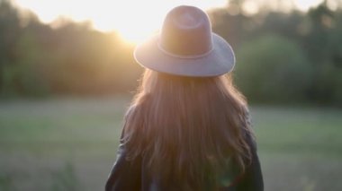 Şapkalı kız gün batımının ışıltısıyla ayrılıyor.