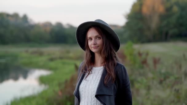 A woman in a hat looks at the camera with curiosity, shyly and attentively — Stock Video