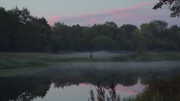 Eine Frau und ein Kind spazieren in der Abenddämmerung im Nebel am Ufer des Sees