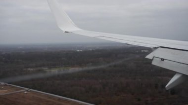 Ticari uçak kanadı, kanatlarını açıp havaalanı pistine iniyor. Aerodinamik yoğunlaşma girdabı, bulutlu bir günde, alanlara son yaklaşma sırasında kanat ucundan itibaren devam eder..