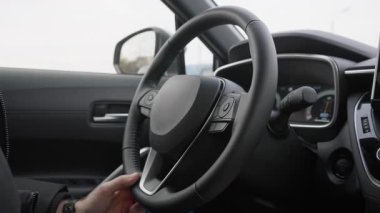 Modern hibrit arabanın deri direksiyonunu tutan adam. Şehir trafik akışında, enerji kurtarma paneli monitörlü, sürücü kontrol aracı.