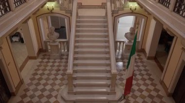 PORDENONE, İtalya - 3 Kasım 2025: Büyük iç merdiven Palazzo del Comune belediye binası mermer basamakları, tarihi büstler ve ahşap bir tavanın altında dekoratif bir mozaik.