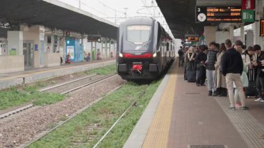 VENEZIA MESTRE, ITALY - 3 Kasım 2025: Modern Trenitalia Rock bölgesel treni istasyon platformuna ulaşır. Çantalı yolcular bulutlu bir sonbahar gününde trene binmek için bekliyorlar..