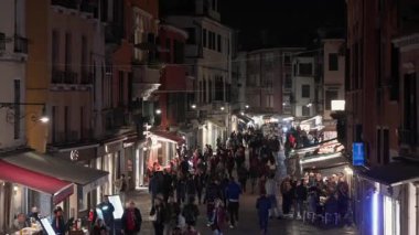 Venedik, İtalya - 3 Kasım 2025: Venedik 'te geceleri dar tarihi bir caddede sıkışıklık yaratan büyük turist kalabalığı. İtalya 'da aşırı turizm ve toplu seyahat sorunlarının görsel bir temsili.