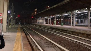 Geceleri parlayan ışıklar ve tren raylarıyla dolu boş bir tren istasyonu platformu. Venedik Ustası seyahati için ulaşım merkezi. Toplu taşıma altyapısı, terk edilmiş şehir terminali manzarası.