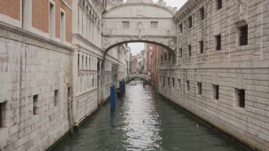 Venedik 'te dar bir kanalda iç çekme köprüsü. Tarihsel beyaz taş mimarisi ve İtalya 'nın ünlü simgesi. Bulutlu gökyüzü ve bulutlu hava koşulları altında turist gezisi.