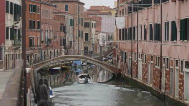 Sürat teknesi dar bir Venedik kanalından taştan kemerli bir köprüye doğru ilerliyor. İtalya 'da çamaşır ipleri asılmış tarihi konut binaları. Otantik yerel yaşam tarzı ve manzarası.