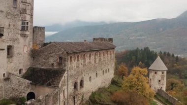 Antik ortaçağ taş kalesi, sonbahar ormanı ve sisli dağlarla çevrili tepenin üzerinde duruyor. Duvarları ve kuleleri olan tarihi şato mimarisi Avrupa 'daki manzaralı vadi manzarasına bakıyor.