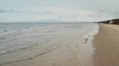 Jurmala Letonya 'da yüksek açılı kum kıyısı ve Baltık Denizi dalgaları. Çevre koruma ve turizm sektörü geçmişi için kırılgan kuzey doğası ve kıyı erozyonu teması.