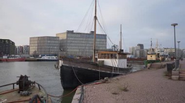 Finlandiya 'nın başkentinin deniz manzarasının bulutlu sonbahar gününde Helsinki Ruoholahti limanında modern ofis mimarisine karşı demirlemiş klasik ahşap yelkenli tekne..