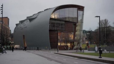HELSINKI, FINLAND - 10 Aralık 2025: alacakaranlıkta Kiasma Çağdaş Sanat Müzesi. Yayalar şehir merkezindeki modern mimari yapı ve galeriyi yürüyerek geçiyorlar..