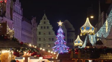 Polonya 'nın Wroclaw kentindeki bayram pazarının en önemli parçası büyük aydınlatılmış bir Noel ağacı. Turist kalabalığı tatil panayırlarının ve kış şehir atmosferinin tadını çıkarıyor..