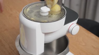 Elektrikli gıda işlemcisi taze patates ve beyaz soğanı ince hamura çevirir. Mutfak aletleri patates gözlemesi için sebze malzemelerini yüksek sesli motor sesiyle karıştırıyor..
