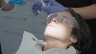 Profesyonel diş pensesi kullanarak cerrahi müdahaleyle dişlerin alınması. Modern stomatoloji kliniğindeki genç hasta çenesinden geçici diş hekimliği alınıyor.