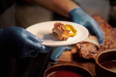 Otel çalışanlarının eli kapalıdır. Tabakta barbekü rafı kesilir.