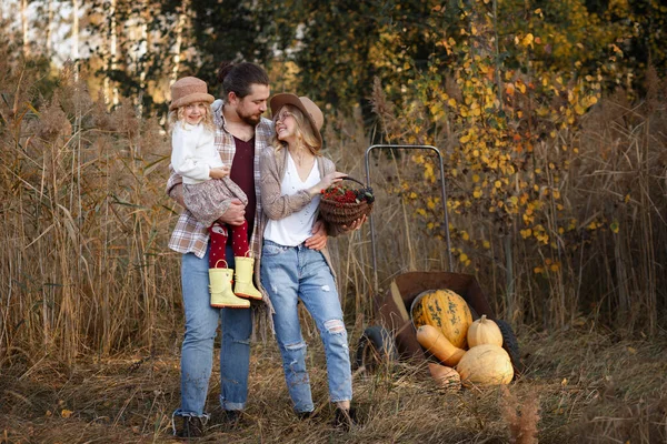 Happy family of farmers with pumpkin harvest in autumn