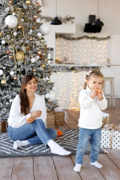 Chica Come Mandarina Fondo Mamá Árbol Navidad — Foto de Stock