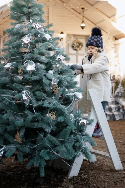 Kız kışın bir Noel ağacını süslüyor