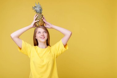 Sarı arka planda ananaslı çekici bir kız.