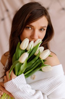 Kadın beyaz laleleri kokluyor.