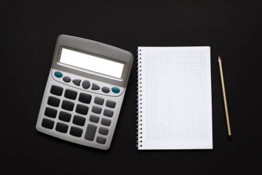 Siyah arkaplan üzerinde hesap makinesi, not defteri ve kalem