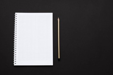 Siyah arkaplanda beyaz kağıt not defteri ve kalem.