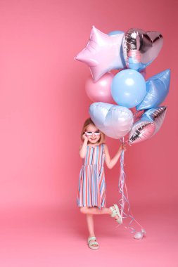 Kız pembe arka planda balonlarla dans ediyor