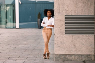 Binanın dışında koyu tenli bir kadın var.