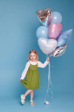 Mavi arka planda balonları olan küçük bir kız.
