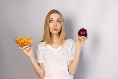 Kadın arka planda cips ve elma arasında seçim yapar