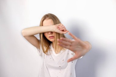 Kadın gözlerini kapar ve beyaz bir arka planda dur işareti gösterir.