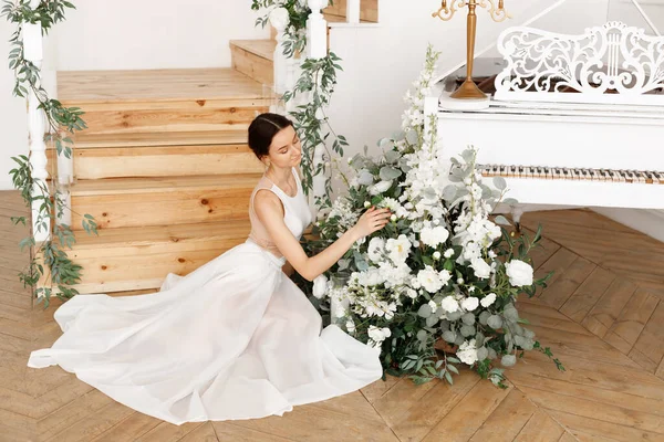 attractive elegant girl near the piano with flowers