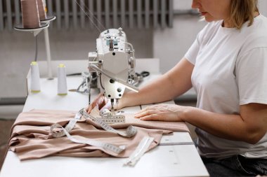 Fabrikada dikiş makinesinin arkasında bir terzi.