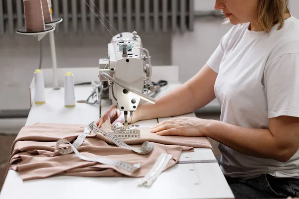 a seamstress behind a sewing machine in a factory