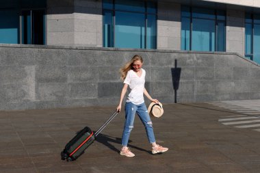 Yaz seyahatinde el bagajı taşıyan genç kız.