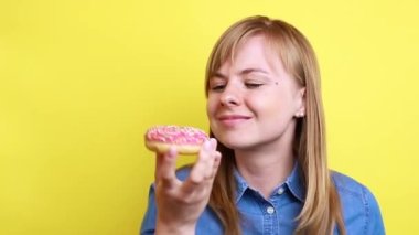 Kız sarı arka planda lezzetli bir donut kokluyor..