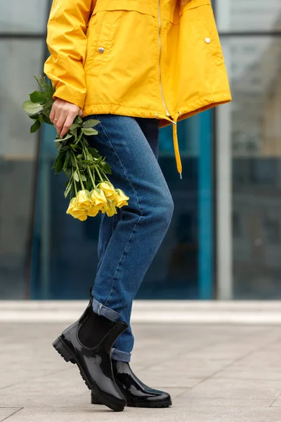 woman in rubber boots with yellow flowers close-up