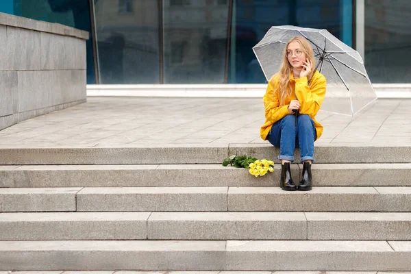 Eine Frau Gelbem Regenmantel Und Gummistiefeln Sitzt Unter Einem Regenschirm — Stockfoto