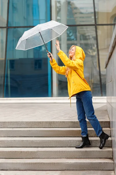 woman in yellow raincoat with umbrella in the city
