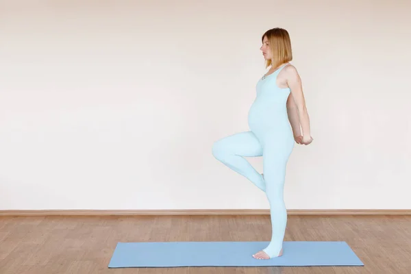 妊娠中のヨガスーツの女性が片方の足に立っています 妊婦のためのヨガ — ストック写真