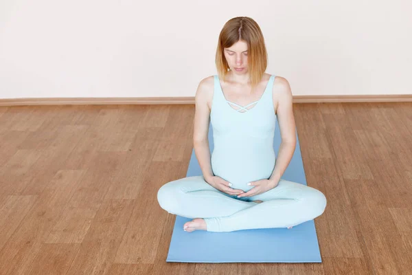 Een Zwangere Vrouw Een Lotuspositie Een Heldere Studio Een Mat — Stockfoto