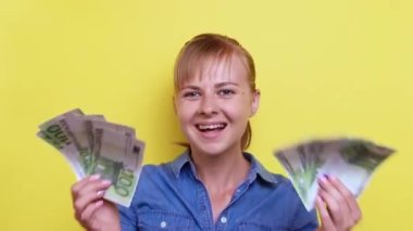 Avro banknotları olan çekici bir kadın sarı arka planda gülüyor ve dans ediyor. Sürpriz, kazandım.