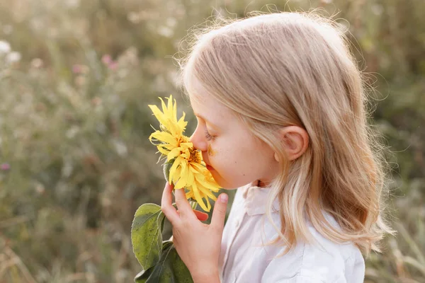 Uma Menina Cheira Uma Flor Amarela Close — Fotografia de Stock