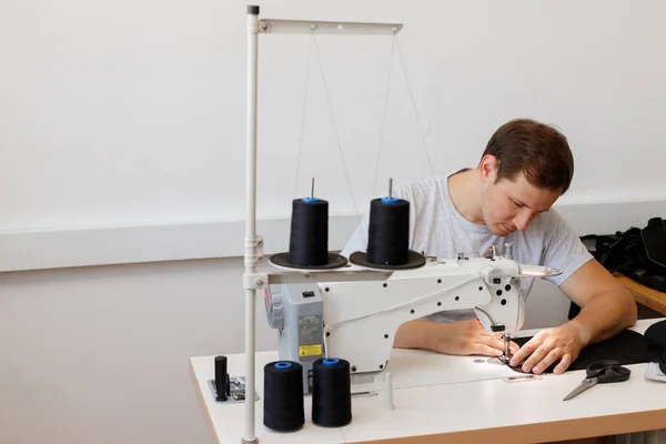 a man behind a sewing machine on a gray background. free space for text