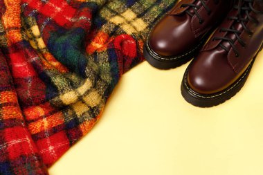 Sonbaharın parlak arka planı. Sarı arka planda kafeslenmiş bir eşarp ve burgundy sıcak botlar. Sonbahar havası