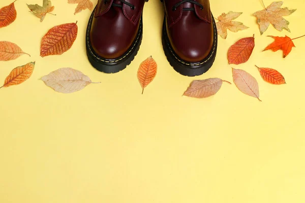Burgunderstiefel Mit Gelben Herbstblättern Auf Gelbem Hintergrund Freiraum Für Text — Stockfoto