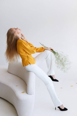 Kanepesinde çiçekler olan şık bir model blogcu. moda havası